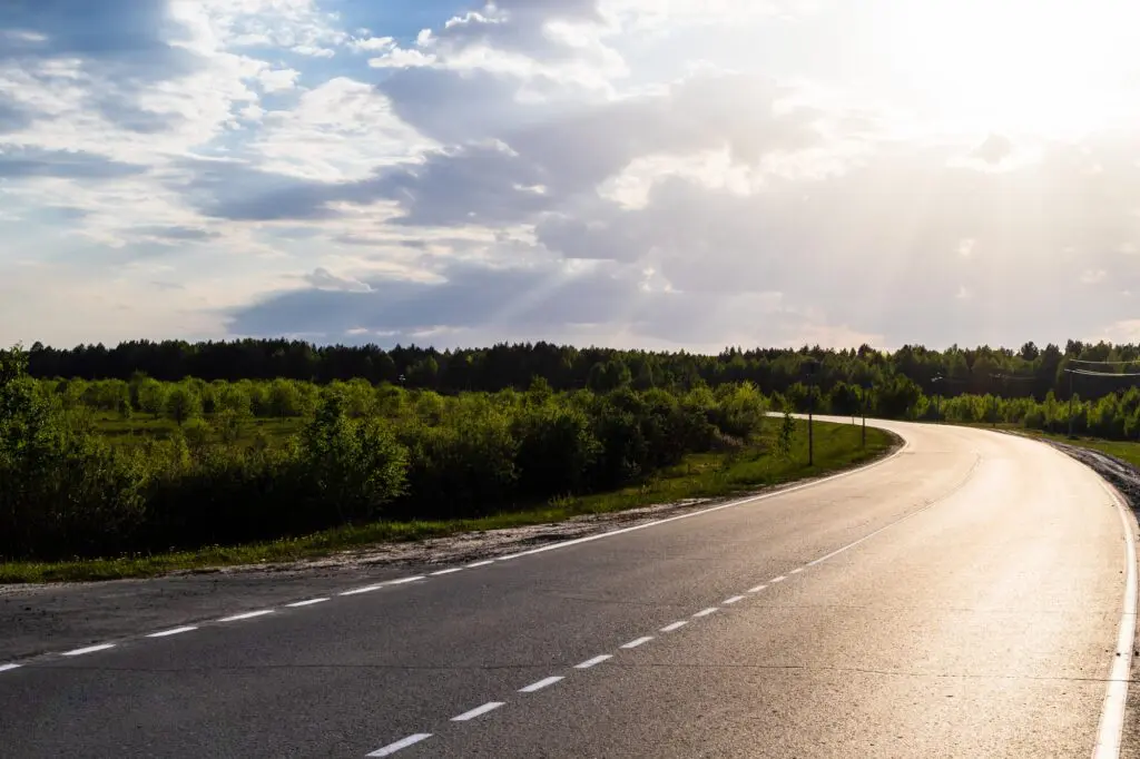 The sunlit road makes a sharp turn.