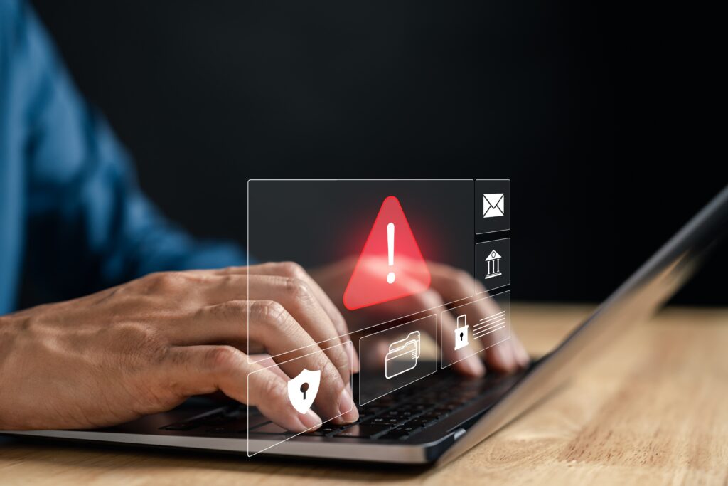 Freight fraud prevention concept showing laptop with warning alert, representing trucking scams like double brokering and carrier identity theft.