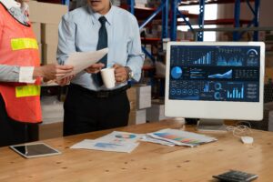 Logistics professionals reviewing freight transportation data and shipment planning information in a warehouse environment